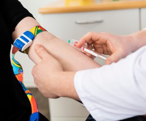 Pielęgniarz w białym fartuchu pobiera mężczyźnie krew z żyły u ręki. /Źródło: 123rf.com