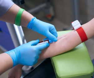 Pielęgniarka w sterylnych warunkach pobiera pacjentowi krew z żyły u ręki pacjentowi. /Źródło: 123rf.com