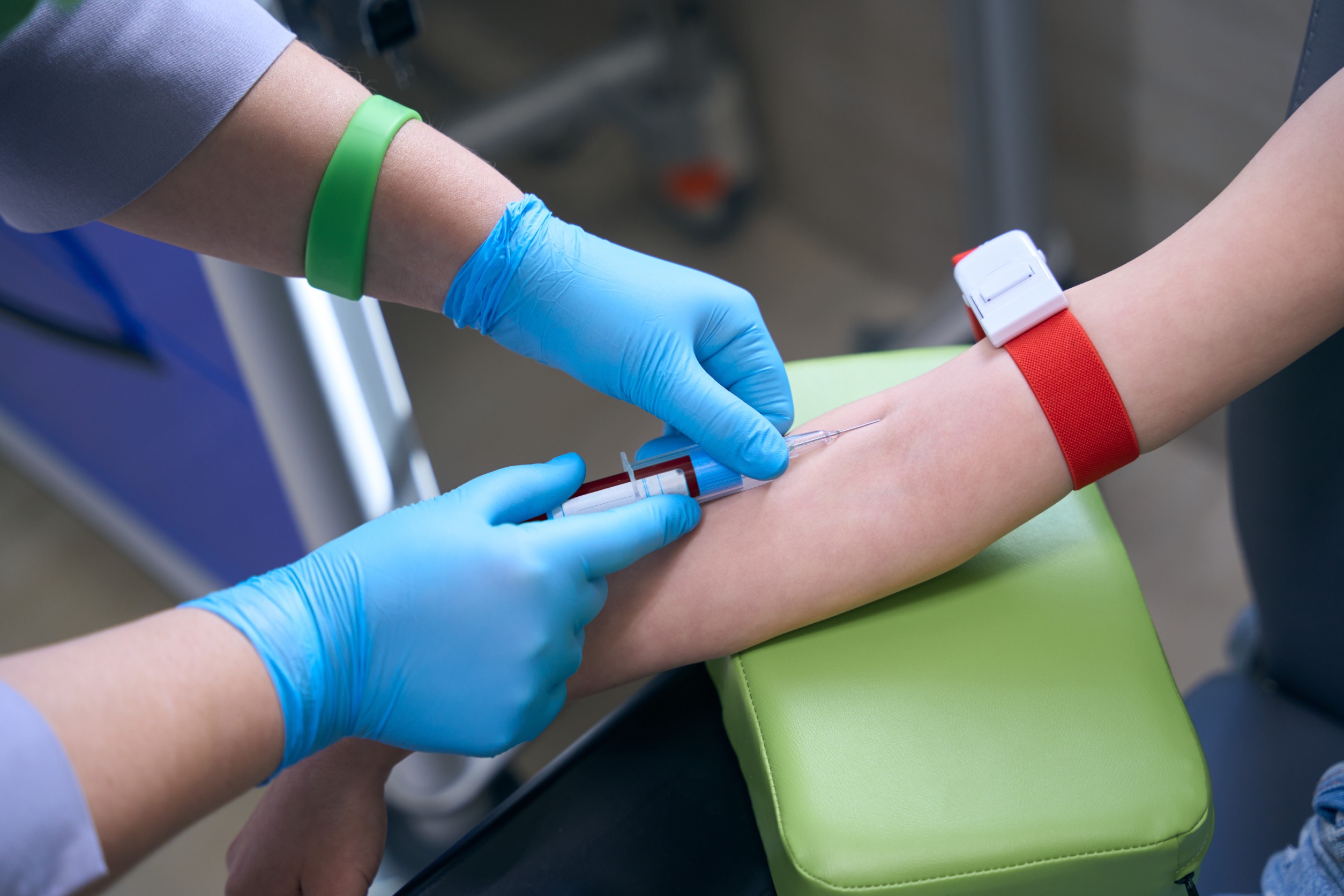Pielęgniarka w sterylnych warunkach pobiera pacjentowi krew z żyły u ręki pacjentowi. /Źródło: 123rf.com