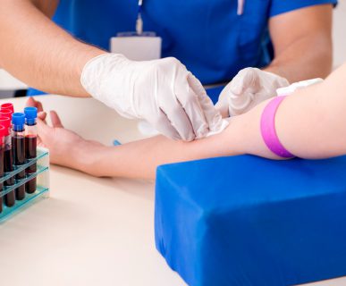 Pielęgniarz dezynfekuje miejsce, w którym będzie wkłuwał igłę, aby pobrać krew pacjentowi. /Źródło: 123rf.com