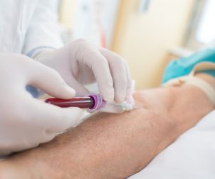 Pielęgniarka pobiera starszemu mężczyźnie krew z żyły u ręki. /Źródło: 123rf.com