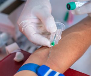 Pielęgniarka wkłuwa igłę w żyłę pacjenta, aby pobrać mu krew do badań diagnostycznych. /Źródło: 123rf.com