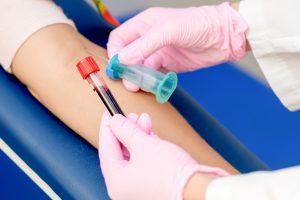 Pielęgniarka w różowych rękawiczkach pobiera pacjentowi krew z żyły u ręki, aby przekazać ją do analizy. /Źródło: 123rf.com