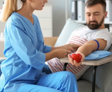 Młoda pielęgniarka w medycznym stroju przygotowuje pacjenta do pobrania próbki krwi zakładając mu opaskę uciskową na ramię. /Źródło: 123rf.com