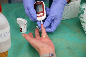 Pielęgniarka mierzy pacjentowi poziom cukru w krwi z opuszki palca za pomocą glukometru. /Źródło: 123rf.com