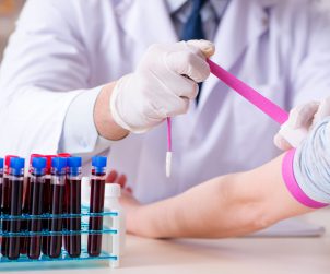 Pielęgniarz zaciska pacjentce różową opaskę zaciskową na ramieniu, w celu sprawniejszego pobrania krwi. /Źródło: 123rf.com