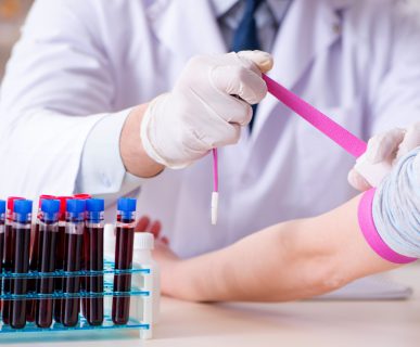 Pielęgniarz zaciska pacjentce różową opaskę zaciskową na ramieniu, w celu sprawniejszego pobrania krwi. /Źródło: 123rf.com