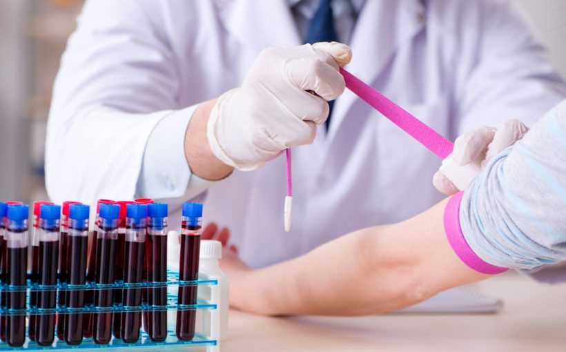 Pielęgniarz zaciska pacjentce różową opaskę zaciskową na ramieniu, w celu sprawniejszego pobrania krwi. /Źródło: 123rf.com