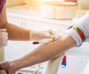 Pielęgniarka pobiera młodemu mężczyźnie krew z żyły u ręki. /Źródło: 123rf.com