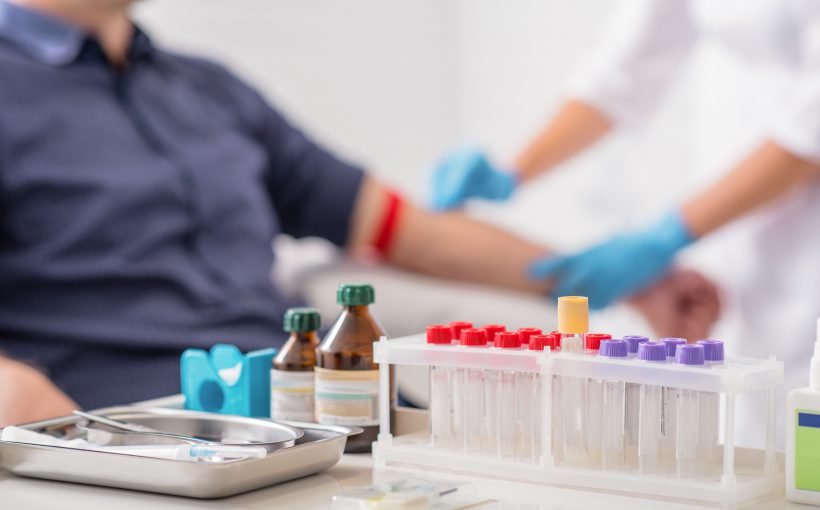 Narzędzia medyczne, w tle których pielęgniarka pobiera mężczyźnie krew z żyły u ręki w celu diagnostyki laboratoryjnej. /Źródło: 123rf.com