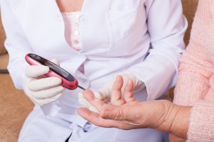 Pielęgniarka mierzy starszej pacjentce poziom glukozy we krwi z opuszki palca. /Źródło: 123rf.com