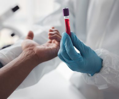 Pielęgniarz trzyma w dłoni probówkę wypełnioną krwią pacjenta, po pobraniu jej pacjentowi. /Źródło: 123rf.com
