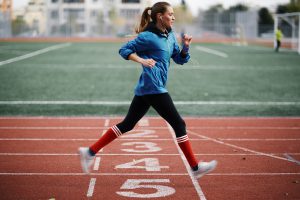 Młoda kobieta w sportowym ubraniu biegnie na stadionie lekkoatletycznym. /Źródło: 123rf.com