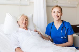Lekarka i leżąca w łóżku pacjentka uśmiechają się do obiektywu. /Źródło: 123rf.com
