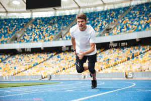 Sportowiec biegnie po torze wyścigowym na stadionie. /Źródło: 123rf.com