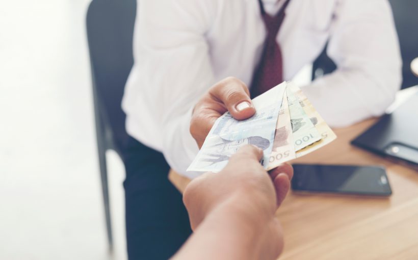 Pacjent wręcza lekarzowi łapówkę. /Źródło: 123rf.com