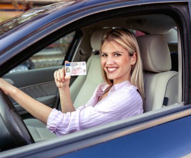 Kobieta w niebieskim aucie, prezentuje swoje prawo jazdy. /Źródło: 123rf.com