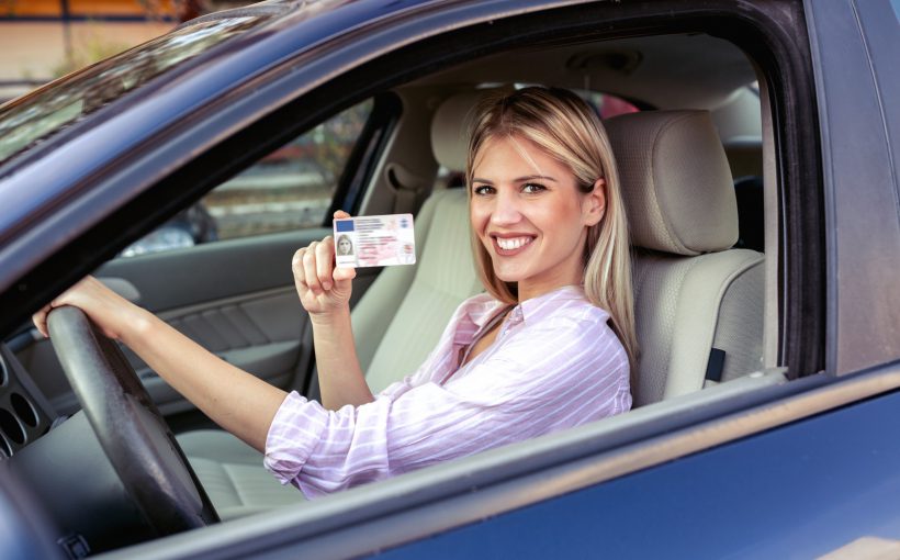 Kobieta w niebieskim aucie, prezentuje swoje prawo jazdy. /Źródło: 123rf.com
