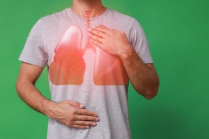 Mężczyzna trzyma się za klatkę piersiową w miejscu płuc, które go bolą. /Źródło: 123rf.com
