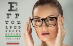 Młoda kobieta podczas wizyty u lekarza okulisty przymierza okulary. /Źródło: 123rf.com