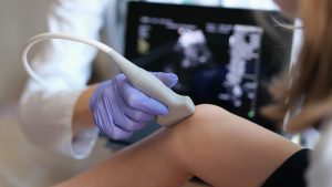 Lekarz wykonuje pacjentce USG kolana. /Źródło: 123rf.com
