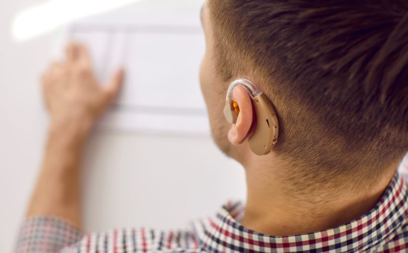 Młody mężczyzna z założonym aparatem słuchowym na ucho. /Źródło: 123rf.com