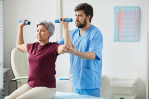 Lekarz rehabilitant uczy pacjentkę jak poprawnie ćwiczyć, aby poprawić swój stan zdrowia. /Źródło: 123rf.com