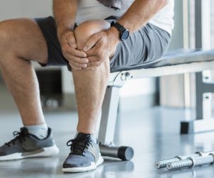 Mężczyzna trzyma się za bolące kolano po urazie podczas ćwiczeń na siłowni. /Źródło: 123rf.com
