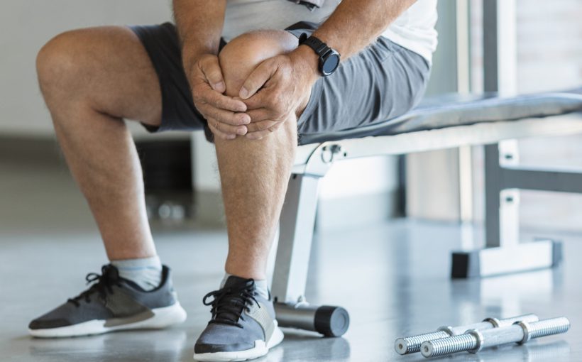 Mężczyzna trzyma się za bolące kolano po urazie podczas ćwiczeń na siłowni. /Źródło: 123rf.com