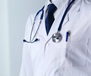 Lekarz stoi ubrany w biały fartuch, na szyi ma stetoskop. /Źródło: 123rf.com