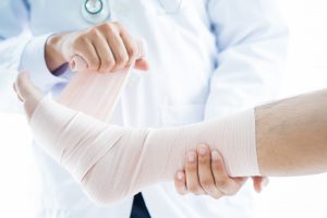 Lekarz ortopeda bandażuje stopę pacjenta po urazie. /Źródło: 123rf.com