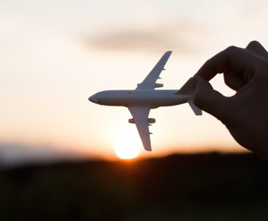 Kobieta trzyma model samolotu na tle zachodzącego słońca. /Źródło: 123rf.com
