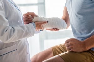 Lekarz zakłada bandaż na rękę pacjenta po urazie. /Źródło: 123rf.com