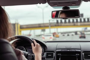 Kobieta prowadzi auto, trzymając dłonie na kierownicy. /Źródło: 123rf.com