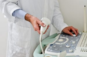Lekarz ubrany w biały fartuch medyczny przygotowuje się do  rozpoczęcia pracy i wykonywania USG. /Źródło: 123rf.com