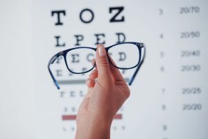 Kobieta trzyma w dłoni okulary porównując różnice z wadą wzroku. /Źródło: 123rf.com