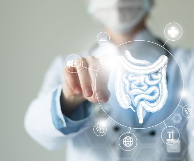 Lekarz ubrany w biały fartuch wskazuje palcem na grafikę jelit. /Źródło: 123rf.com