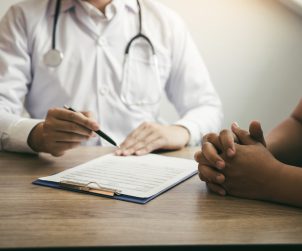 Lekarz medycyny rodzinnej przeprowadza konsultacje lekarską z zaniepokojonym swoim stanem zdrowia pacjentem. /Źródło: 123rf.com