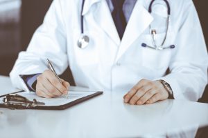 Lekarz internista przeprowadza konsultacje lekarską, wypełnia zaświadczenie. /Źródło: 123rf.com