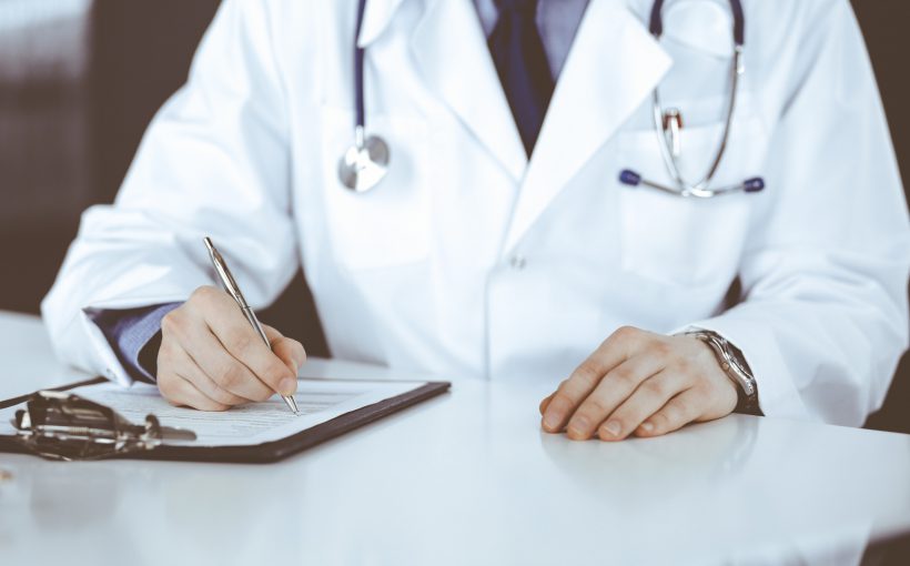 Lekarz internista przeprowadza konsultacje lekarską, wypełnia zaświadczenie. /Źródło: 123rf.com