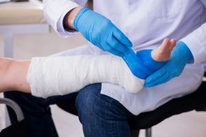 Lekarz ortopeda nakłada pacjentowi bandaż na złamaną nogę. /Źródło: 123rf.com
