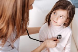 Lekarz pediatra osłuchuje dziewczynkę stetoskopem w celu diagnostyki potencjalnych chorób układu oddechowego. /Źródło: 123rf.com