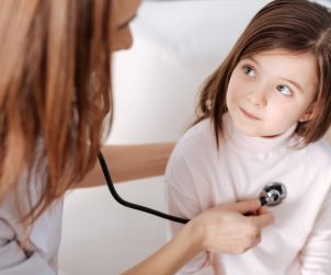 Lekarz pediatra osłuchuje dziewczynkę stetoskopem w celu diagnostyki potencjalnych chorób układu oddechowego. /Źródło: 123rf.com