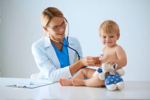 Młoda lekarka pediatra bada uśmiechniętego chłopczyka stetoskopem. /Źródło: 123rf.com