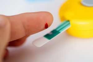 Kobieta mierzy swój poziom cukru przez ukłucie opuszki palca i zmierzenie krwi glukometrem. /Źródło: 123rf.com