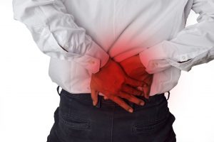 Mężczyzna trzyma dłonie na plecach w miejscu gdzie znajdują się nerki, które go bolą. /Źródło: 123rf.com