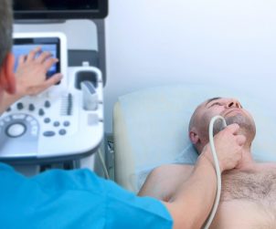 Lekarz wykonuje USG tarczycy pacjentowi leżącemu na kozetce. /Źródło: 123rf.com