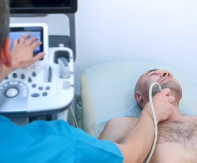 Lekarz wykonuje USG tarczycy pacjentowi leżącemu na kozetce. /Źródło: 123rf.com