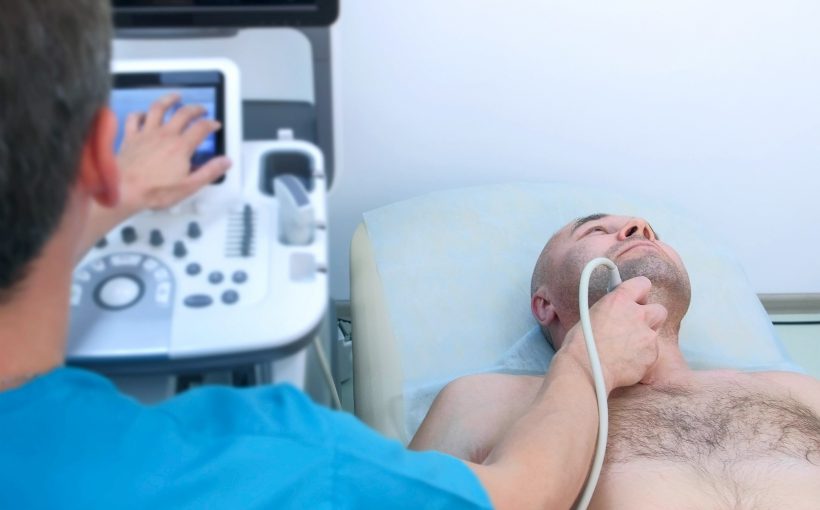 Lekarz wykonuje USG tarczycy pacjentowi leżącemu na kozetce. /Źródło: 123rf.com