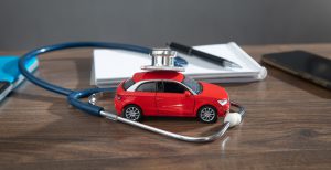 Biurko lekarza orzecznika, na którym położone jest czerwone auto i stetoskop. /Źródło: 123rf.com